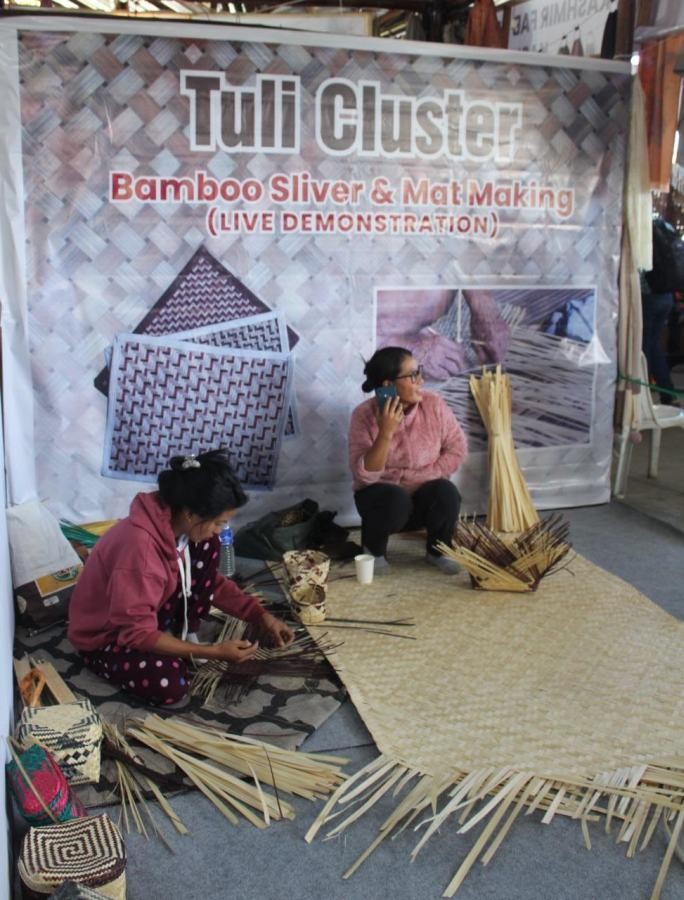 Women artisans of Tuli working on making bamboo mats and baskets the Hornbill Festival, Kisama. The live demonstration by these women artisans is a rare sight as these crafts are mostly male dominated. The artisans shared that in Tuli, bamboo sliver and mat making is an art common to women and the knowledge is generally known among women, young and old. According to the Tuli Cluster, they are women of ten who have also participated in the past to showcase their art through live demonstration. (Morung Photo)